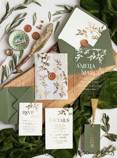 the wedding stationery is laid out on top of green leaves and gold foil accents