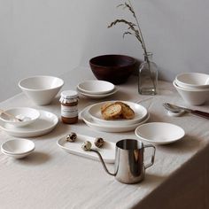 a table topped with white plates and bowls