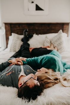 two people laying on top of a bed in the middle of a room with white fur