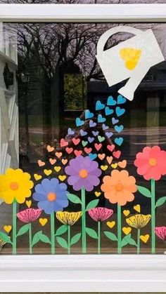 a window decorated with flowers, butterflies and a watering can in the center is a paper cutout