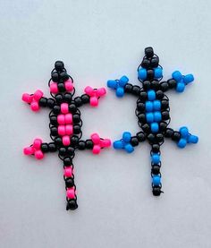 two black, pink and blue beaded crosses on a white surface