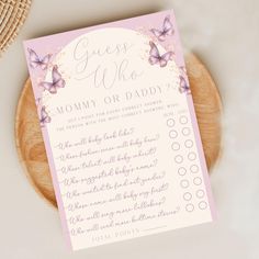 a pink and white baby shower game with butterflies on the front, sitting on a wooden plate