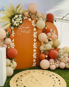 an orange and white wedding arch with flowers on the grass next to a round rug