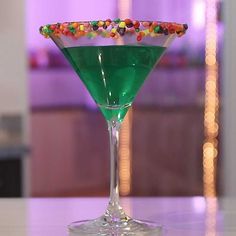 a green martini with candy on the rim and garnished in sprinkles