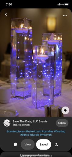 two vases filled with candles sitting on top of a white table covered in blue lights