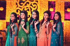 four women dressed in different colored outfits posing for the camera with their hands up and one holding