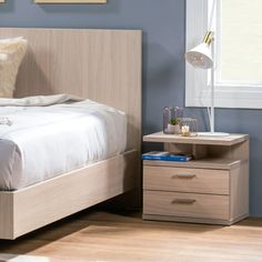 a bed sitting next to a night stand on top of a wooden floor