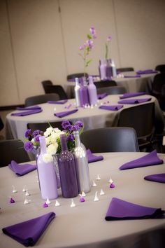 purple and white centerpieces are arranged on the round table at this wedding reception