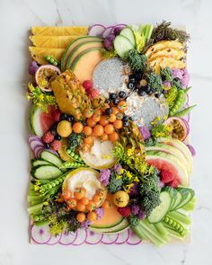 an arrangement of fruits and vegetables arranged on a marble slab with white marble countertop