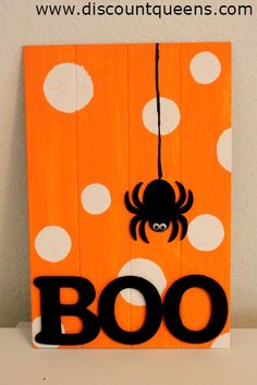 a wooden sign that says boo with a spider hanging from it's center piece