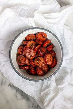 a bowl filled with cooked carrots sitting on top of a white cloth covered table