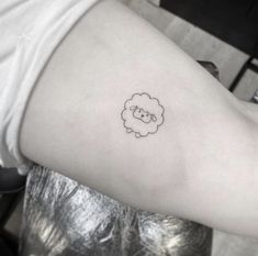 a small sheep tattoo on the left side of the arm, with a black outline