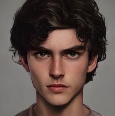 a close up of a young man with curly hair wearing a gray t - shirt