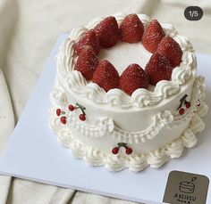 a white cake topped with strawberries on top of a table