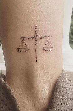 a woman's foot with a tattoo on the ankle that has two scales on it