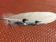 two birds sitting on top of a white feather next to a red and black table