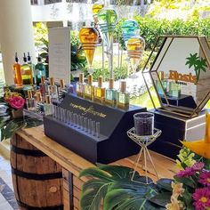 an assortment of bottles and glasses on display at a flower shop with flowers in the background