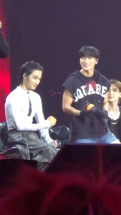 three young men sitting next to each other on stage