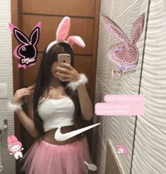 a woman taking a selfie in the bathroom wearing bunny ears and pink tutu skirt