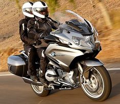 two people riding on the back of a silver motorcycle