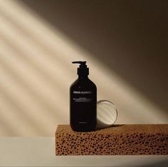 a bottle of lotion sitting on top of a wooden block next to a mirror