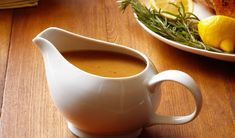 a white pitcher filled with liquid sitting on top of a wooden table next to a bowl of lemons