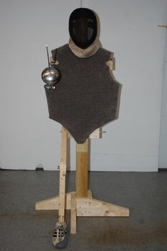 a piece of art made out of wood with a helmet on top and some metal balls attached to it