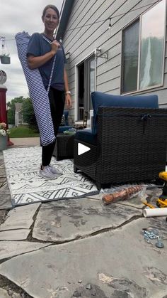 a woman standing on top of a patio next to a black chair and fire hydrant