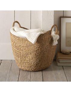 a large woven basket sitting on top of a wooden floor next to a framed photo