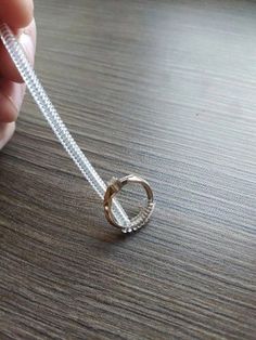 a person holding onto a white string with a ring on it's end and two rings in the middle