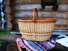 a wicker basket sitting on top of a pile of blankets in front of a log cabin