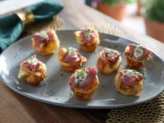 small appetizers with meat and cheese on a silver plate next to a green napkin