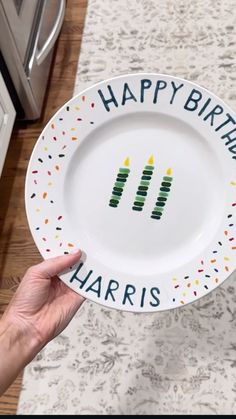 a person holding a happy birthday plate with candles on it