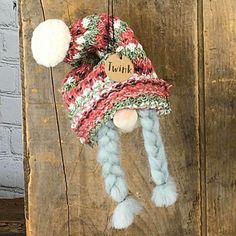 a knitted hat hanging from a wooden door with a name tag attached to it