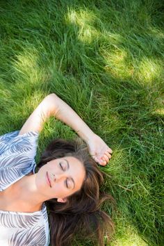 a woman laying in the grass with her eyes closed