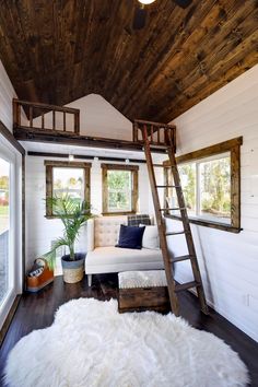 a living room with a white couch and wooden ladders in it's ceiling