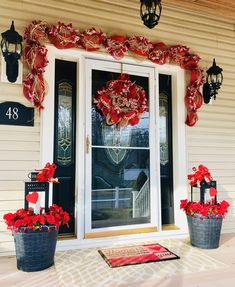 the front door is decorated with red poinsettis and wreaths for christmas