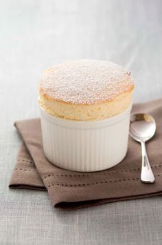 a powdered cake in a white dish on a napkin with a spoon next to it