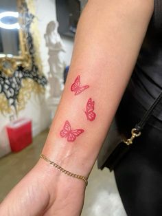 a woman's arm with three pink butterflies on the left side of her wrist