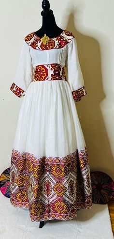 Ethiopian and Eritrean traditional dress (habesha kemis )traditional, flowing design with intricate embroidery. The fabric is primarily white, with vibrant red and yellow embroidery patterns along the neckline, sleeves, waist, and hem. These patterns are geometric and symmetrical, giving the dress a rich, cultural feel. The embroidered details and colors suggest influences from traditional or ethnic textile styles, possibly from regions with rich weaving and embroidery heritage.looks beautiful.elegant habesha clothing Habesha Kemis, Yellow Embroidery, Flow Design, Intricate Embroidery, Embroidered Details, Traditional Dress, Red And Yellow, Silver Spring, Dress Clothes For Women