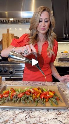 a woman pouring something into a pan with vegetables on the counter in front of her