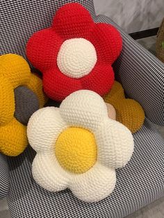 three knitted flowers sitting on top of a chair