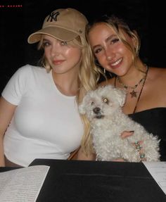 two women are posing with a white dog