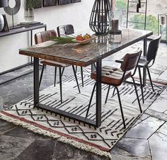 a dining room table with chairs and a rug on the floor in front of it