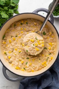 a pot filled with chicken and corn soup on top of a blue towel next to parsley