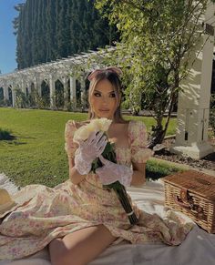 a woman sitting on the ground with flowers in her hand