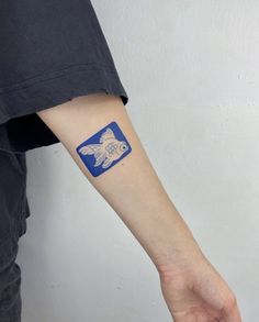 a person's arm with a small blue sticker on it that says fish