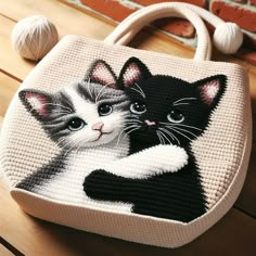 a bag with two cats on it sitting on a wooden table next to balls of yarn