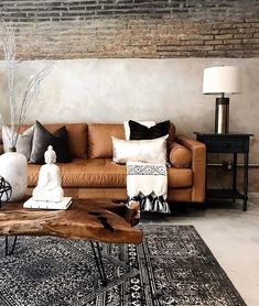 a living room filled with furniture and pillows on top of a wooden table in front of a brick wall