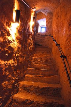 stairs leading up to the light at the end of an underground passage in a stone building